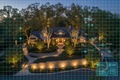 Aerial dusk view of a property with elegant landscape lighting overlaid with a blueprint grid showing fixture placements and wiring paths